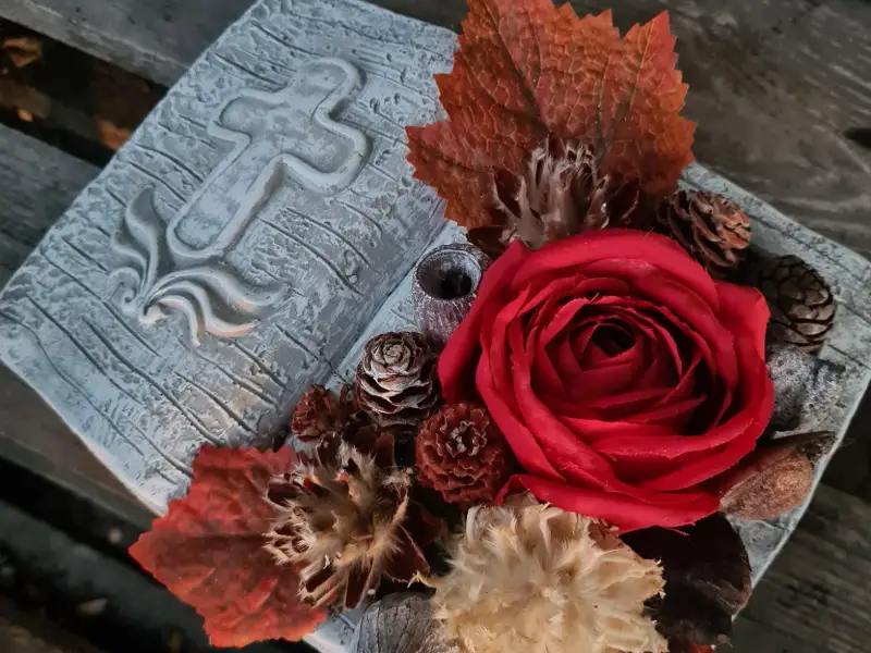 Composition de deuil avec croix, rose rouge et feuillage d'automne